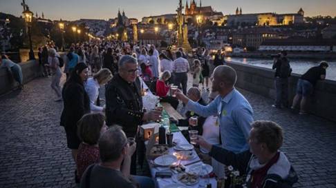 Residents dine at a long table set on the Charles Bridge